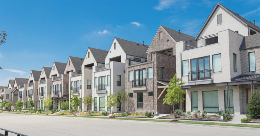 Modern townhouse row with varied architectural designs and greenery in Guelph, Ontario, illustrating residential options for potential buyers.