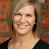 Beth Waller, REALTOR® from Guelph, smiling portrait with a brick background, representing her real estate services and local expertise.