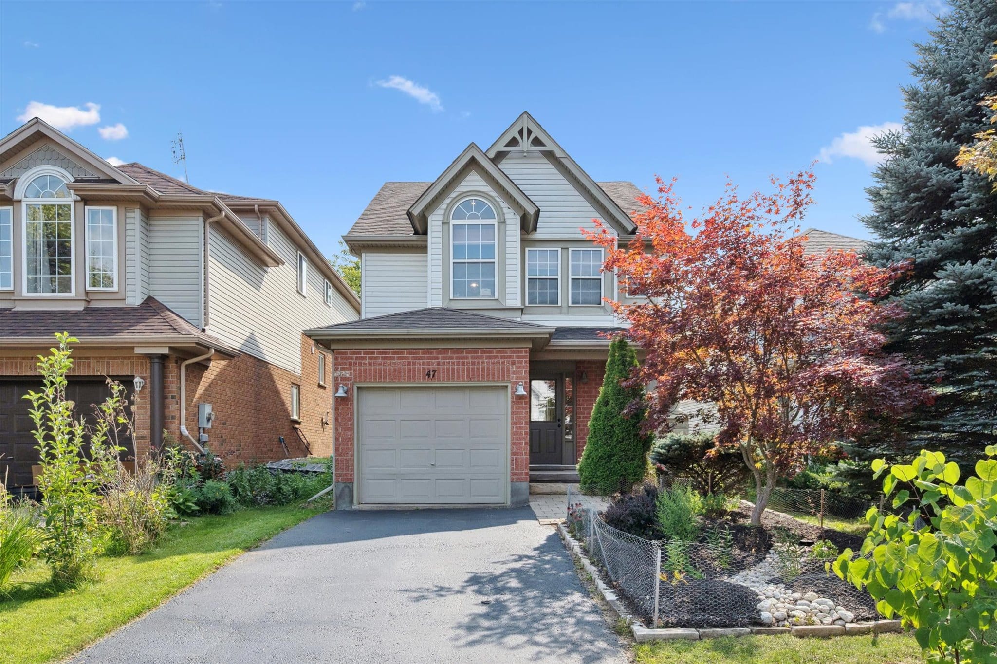 Beautiful family home at 47 Buckthorn Crescent in East Guelph, featuring a well-maintained facade, landscaped yard with colorful foliage, and single-car garage.